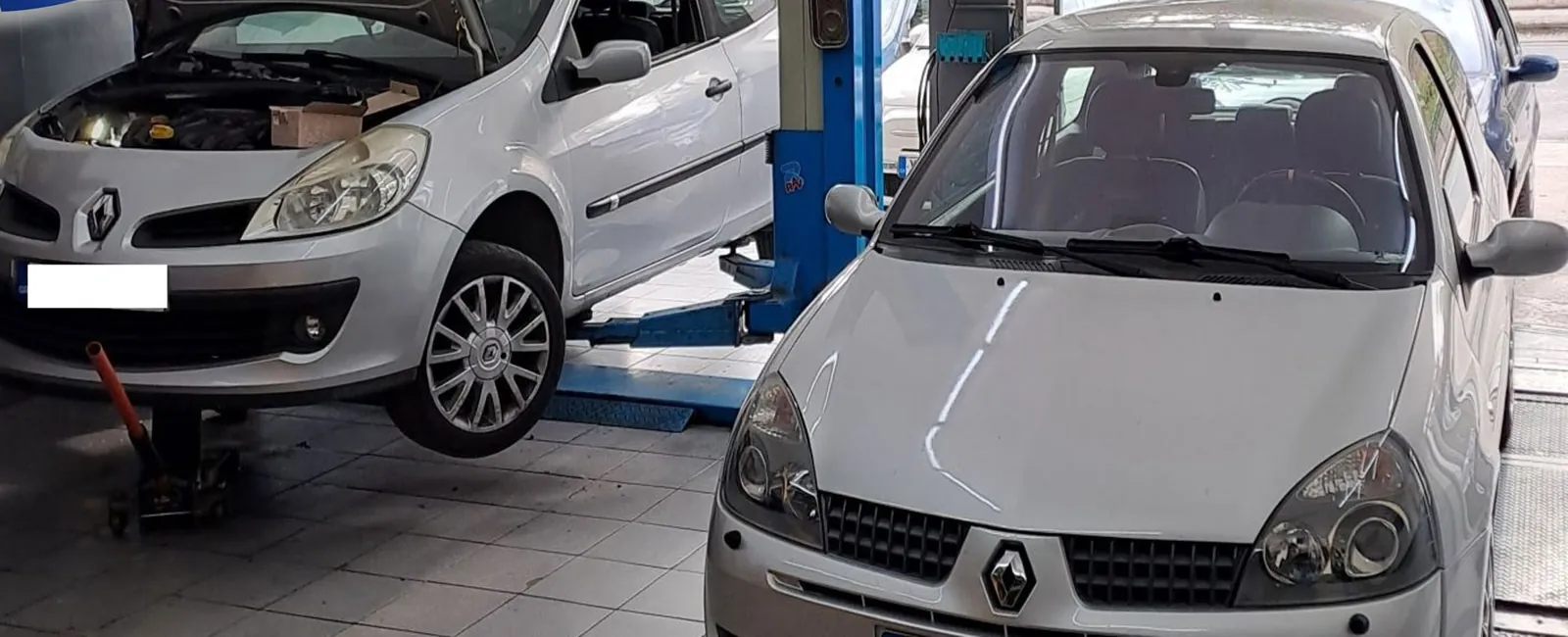Δύο Renault στο συνεργείο, το ένα σηκωμένο στην ανυψωτική πλατφόρμα με ανοιχτό καπό.